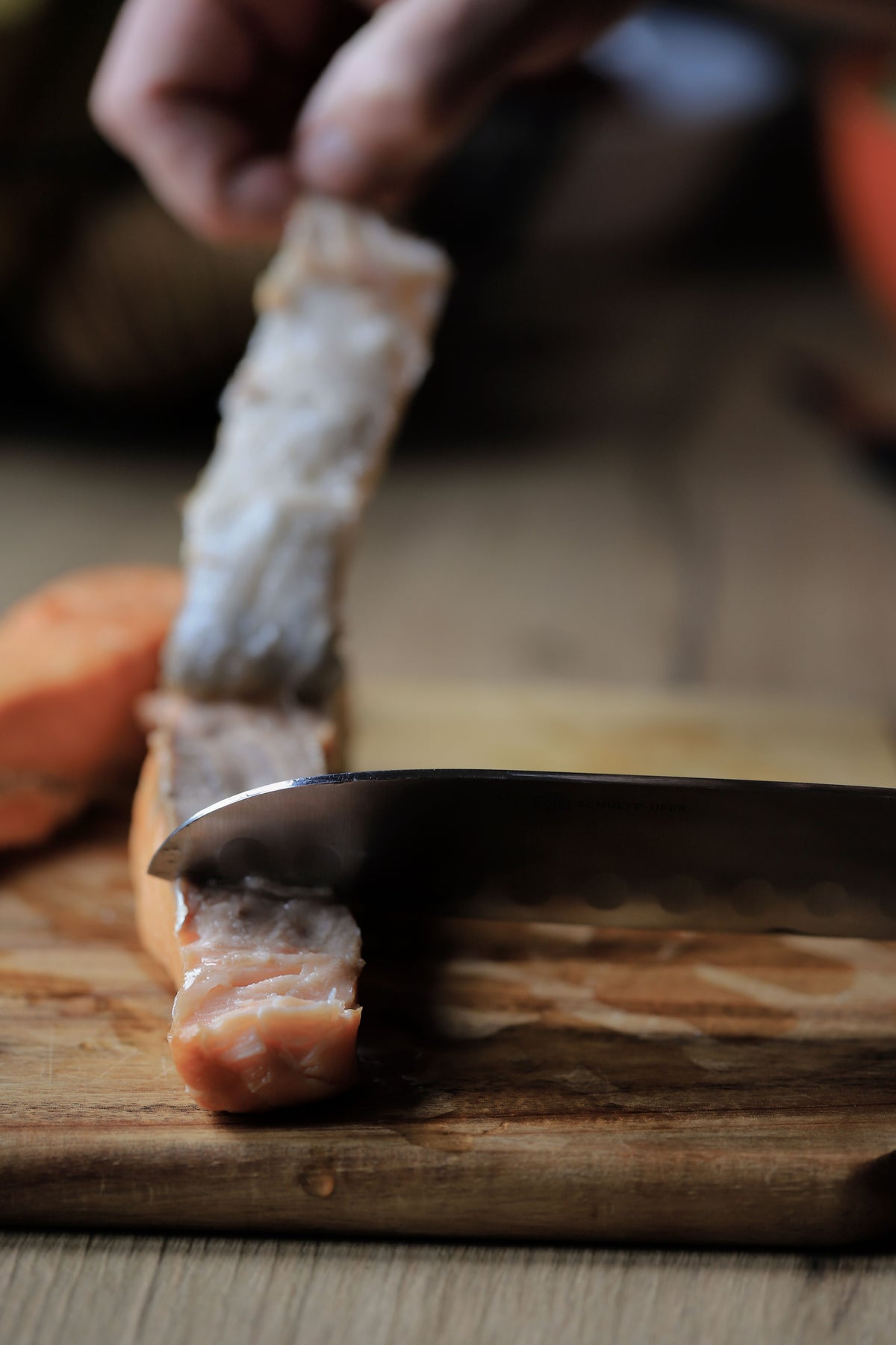 Saumon tranché sur planche en bois, geste de coupe